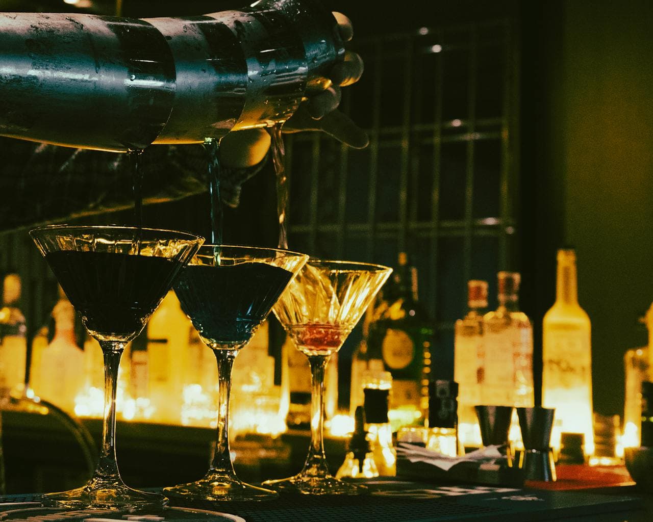 A bartender pouring a cocktail at an event bar